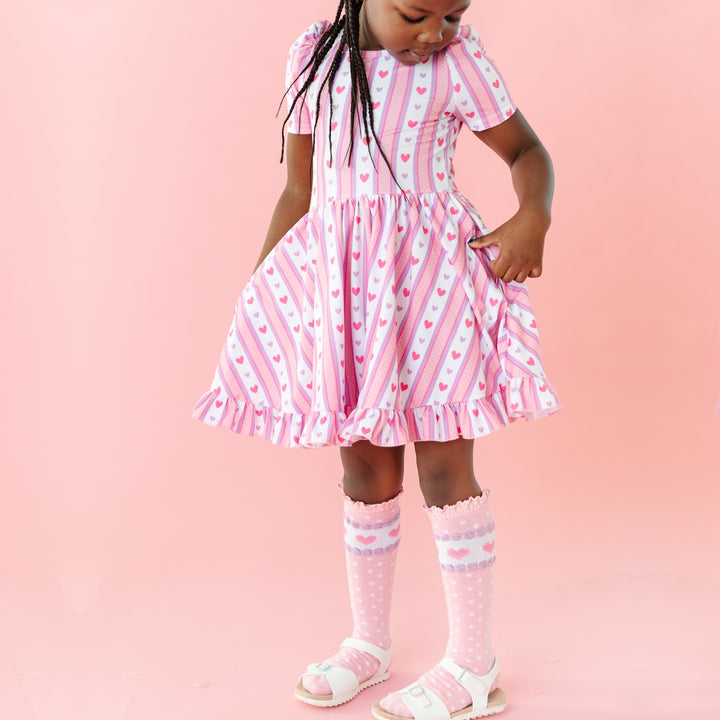 girl in vintage inspired pink and purple heart wallpaper dress with matching pink knee highs with hearts