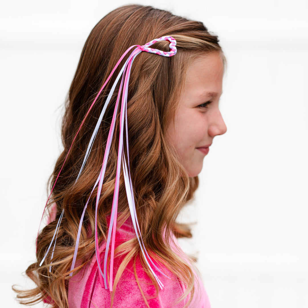 girl with heart shaped hair barrette with braided satin ribbon in pink, white and lavender and long ribbon streamer tail attached