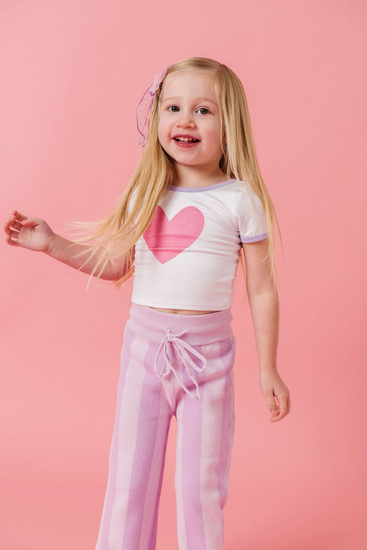 girl in white fitted top with pink heart paired with two tone pastel purple sweater pants for valentines day
