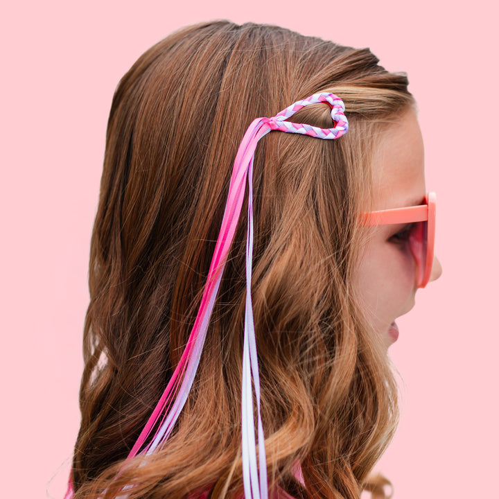 closeup of heart shaped barrette with braided ribbon in pink, white and lavender with streamer ribbon tail