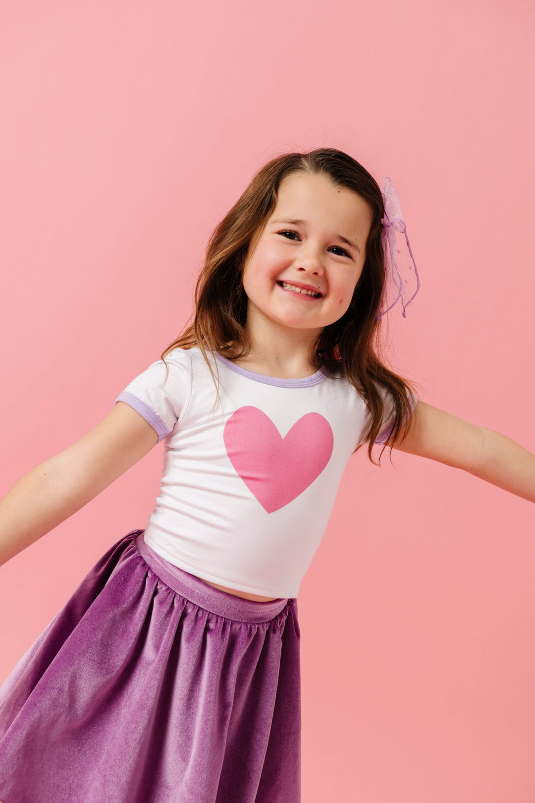 girl in white bamboo top with pink heart design and lavender trim paired with matching lavender velvet skort