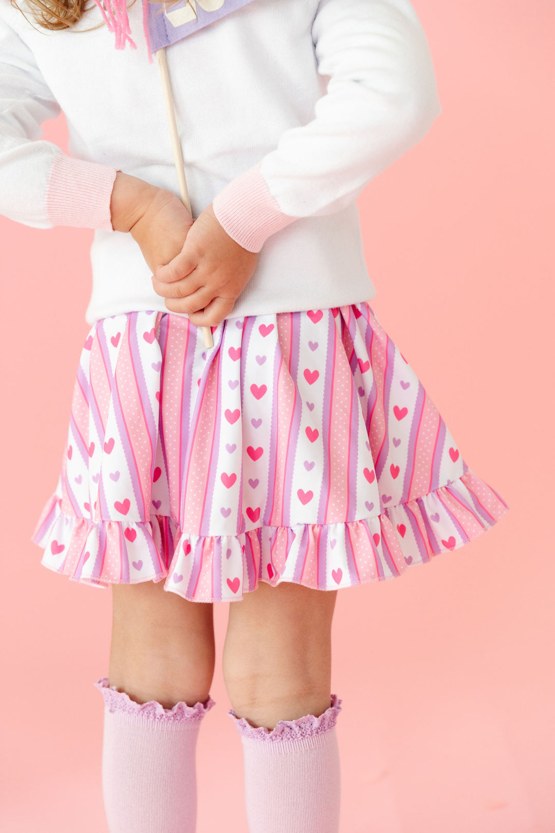 print closeup of little girl in wallpaper inspired pink and lavender heart dress paired with lavender knee highs