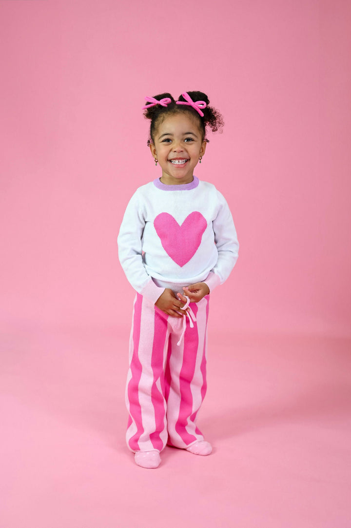 little girl in pink heart pullover sweater paired with matching two tone pink sweater pants and pink yarn pigtail bows for Valentine's Day