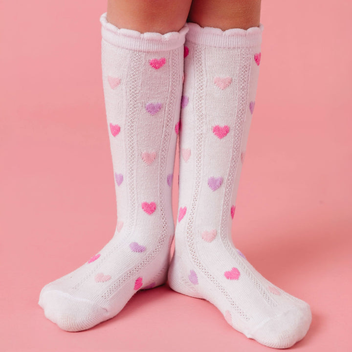 girl standing in white scallop trimmed knee high socks with pastel pink and purple hearts