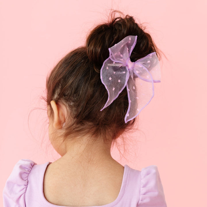 little girl in pink sheer dot party girl bow with purple trim and matching pastel purple dress