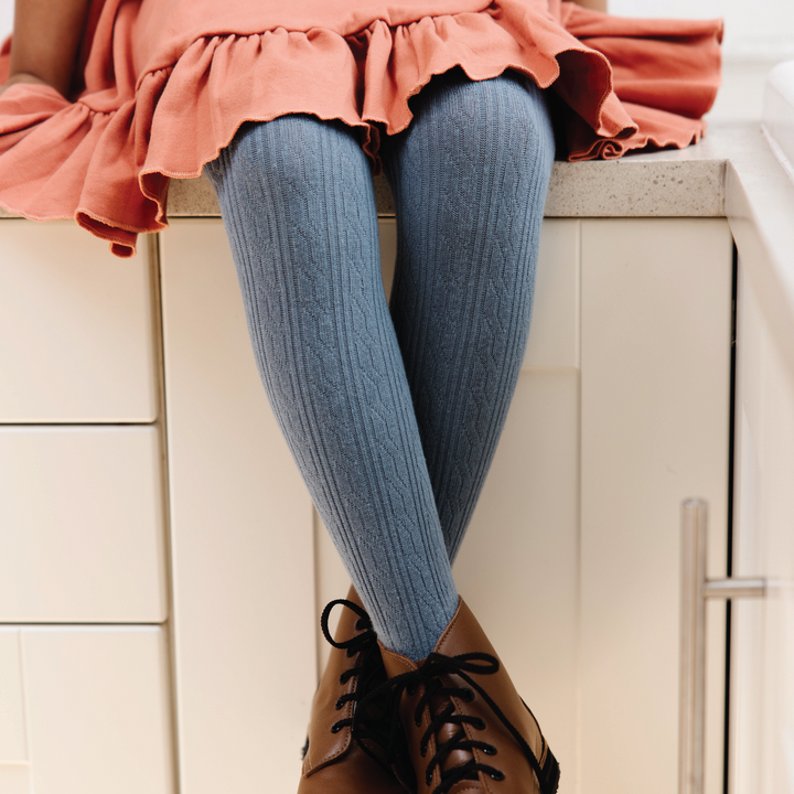 girl in denim cable knit tights sitting on kitchen counter