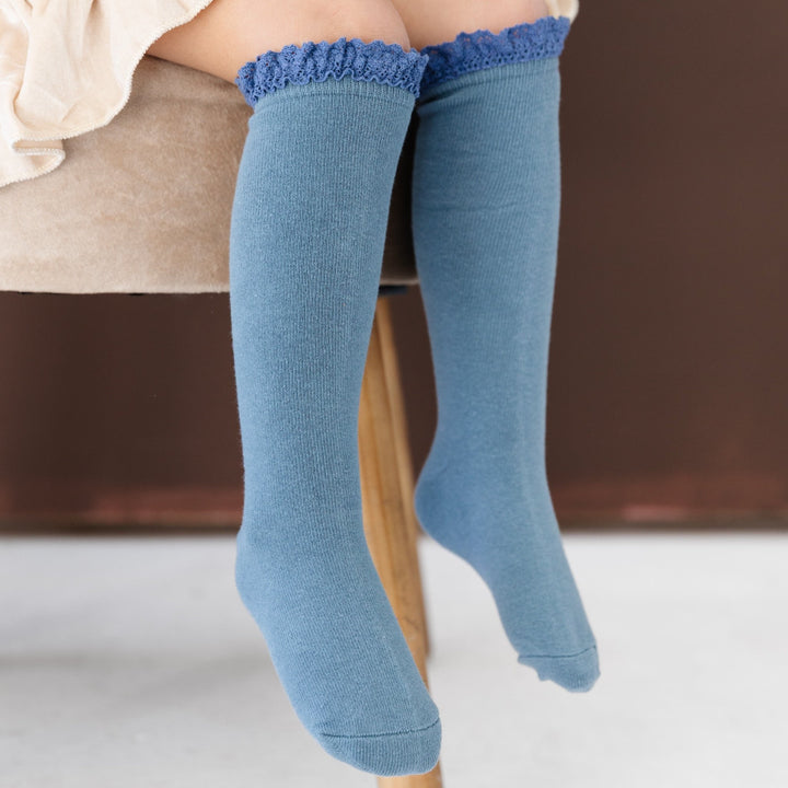 little girl sitting in blue cotton knee highs with blue lace trim