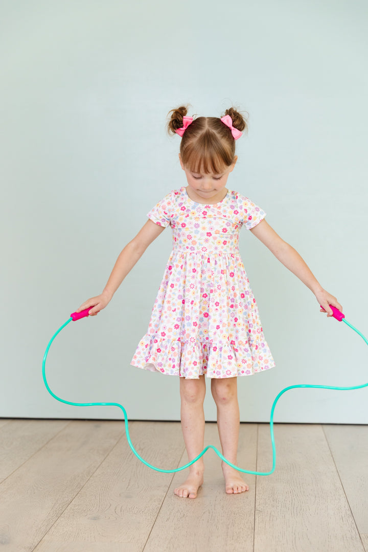 little girl in pastel floral print on white twirl dress for spring and summer playing jumprope