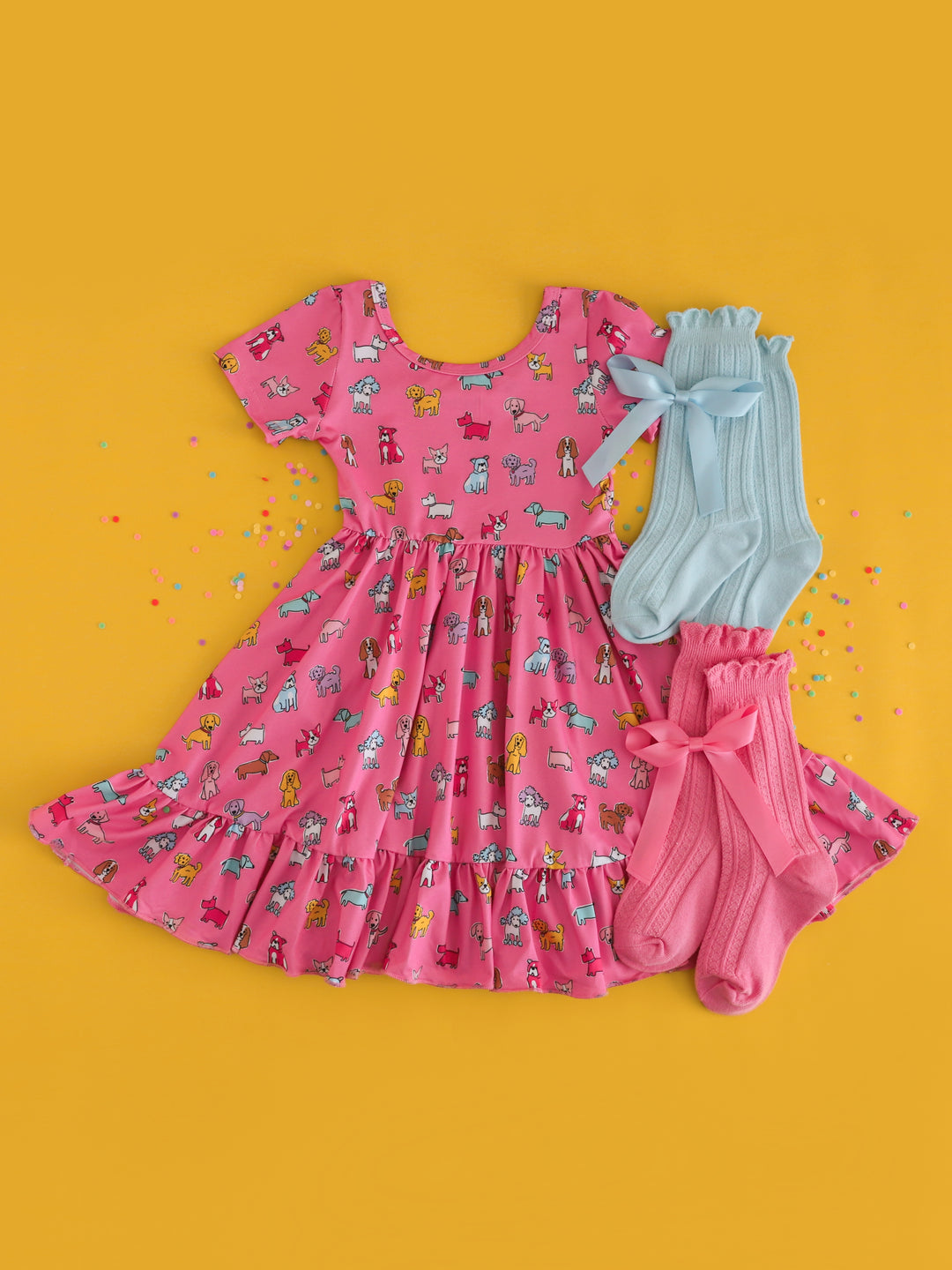 girls pink multicolor dog print twirl dress styled with pink and blue sock and hair bow matches