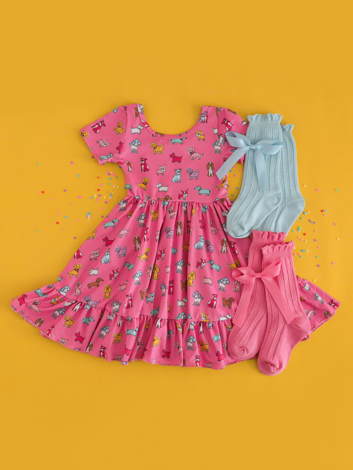 girls pink multicolor dog print twirl dress styled with pink and blue sock and hair bow matches