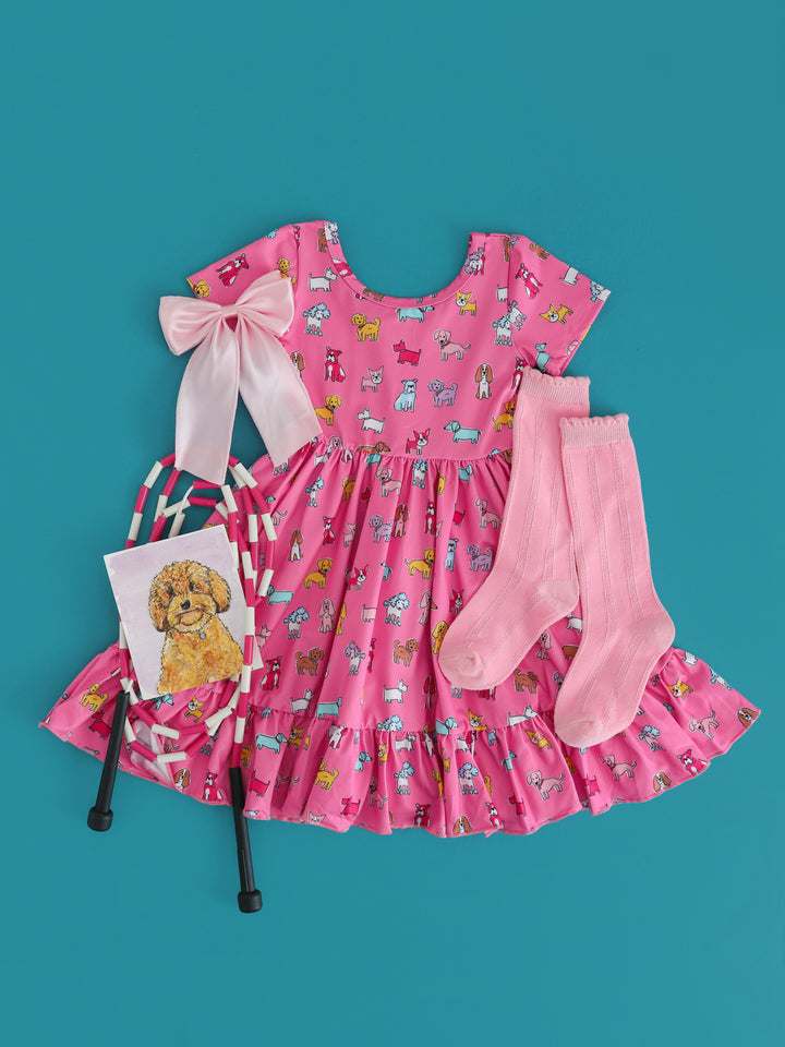 girls bright pink twirl dress with colorful dog print paired with light pink knee highs and satin hair bow