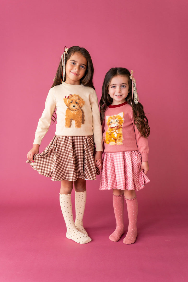 2 little girls wearing knit sweaters with puppy and kitty graphics and matching dresses and polka dot knee high socks