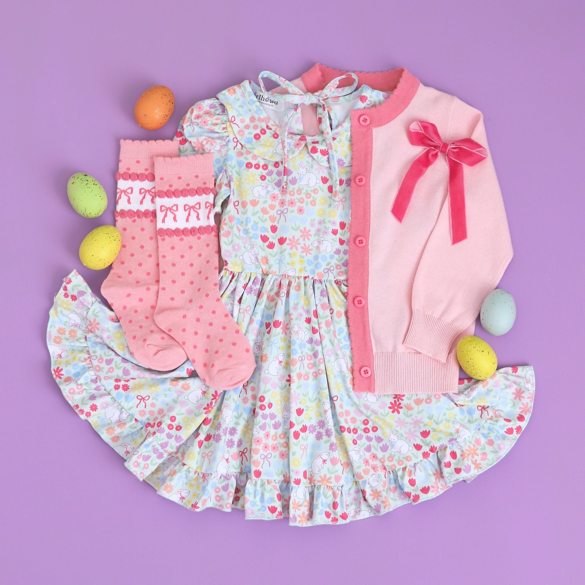 flatlay of girls' easter outfit with floral bunny dress and pink bow socks and cardigan