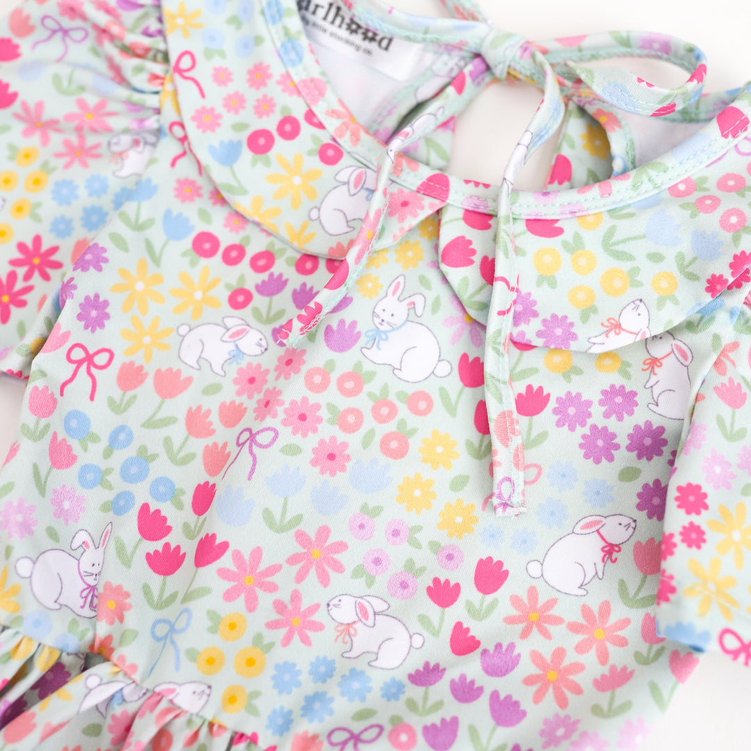 print closeup of girl's collared twirl dress with pastel flowers, bunnies and bows on mint green 