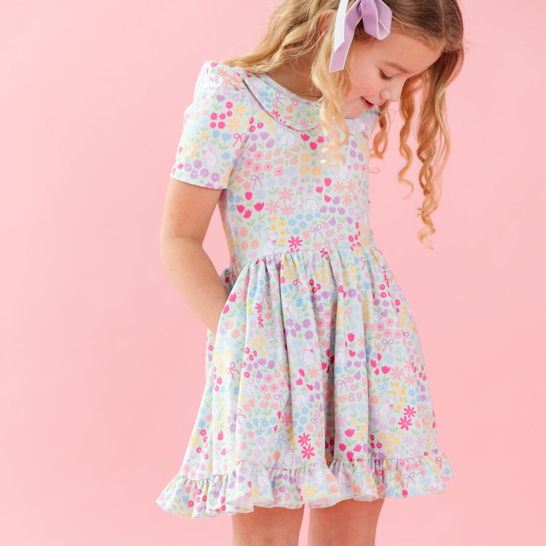 little girl in easter twirl dress with peter pan collar in a pastel flower and bunny print and lavender velvet hair bow 