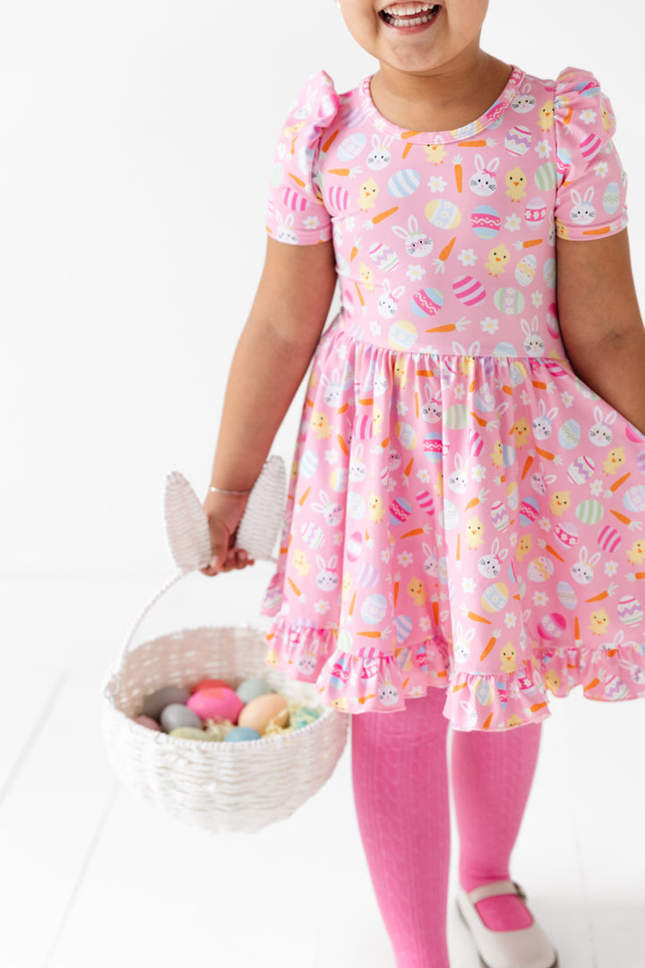 little girl with easter basket in easter print twirl dress with bunnies and chicks and matching pink tights