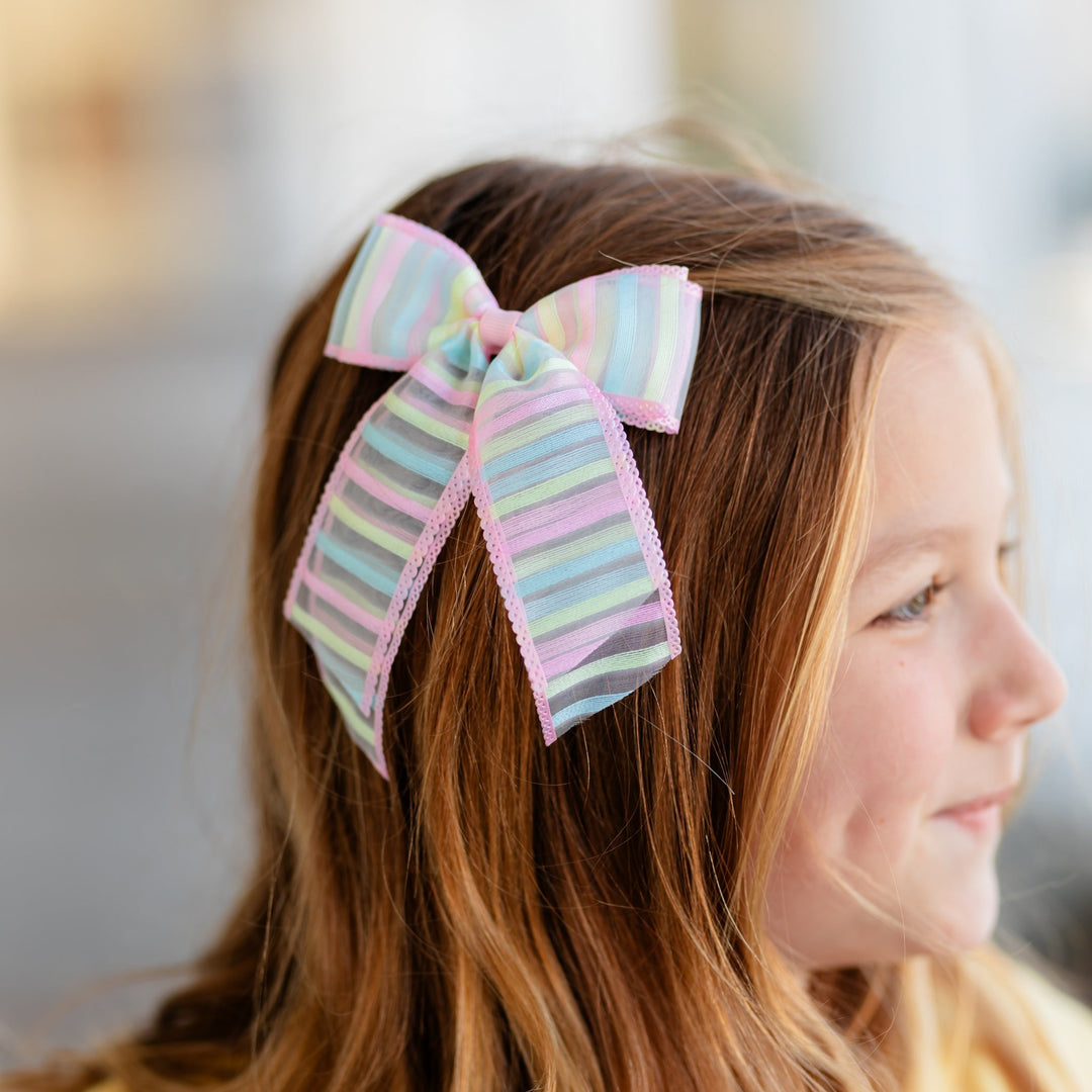 girl in sheer pastel striped hairbow with pink trim for birthday outfit and easter