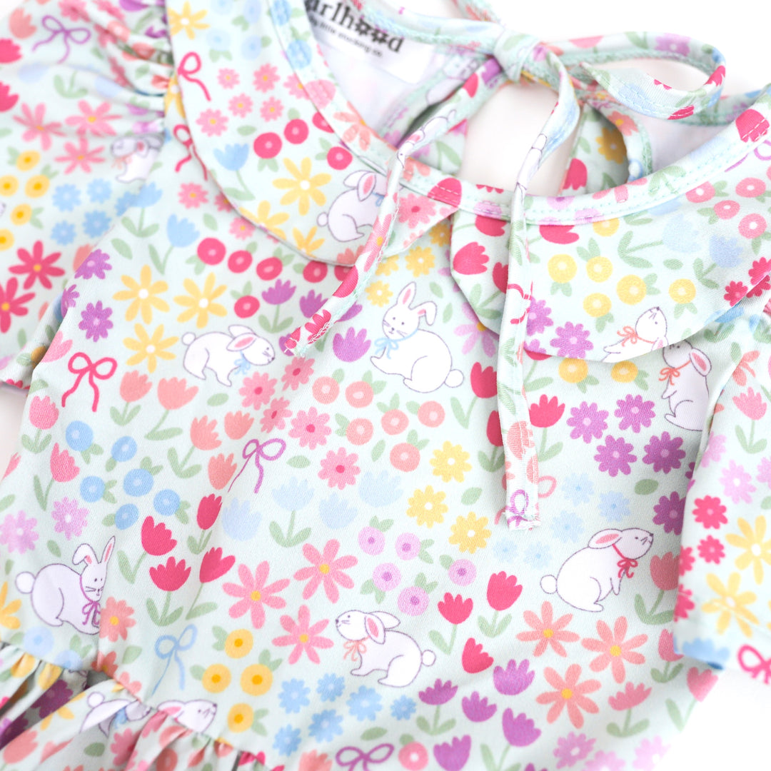 print closeup of girl's collared twirl dress with pastel flowers, bunnies and bows on mint green 