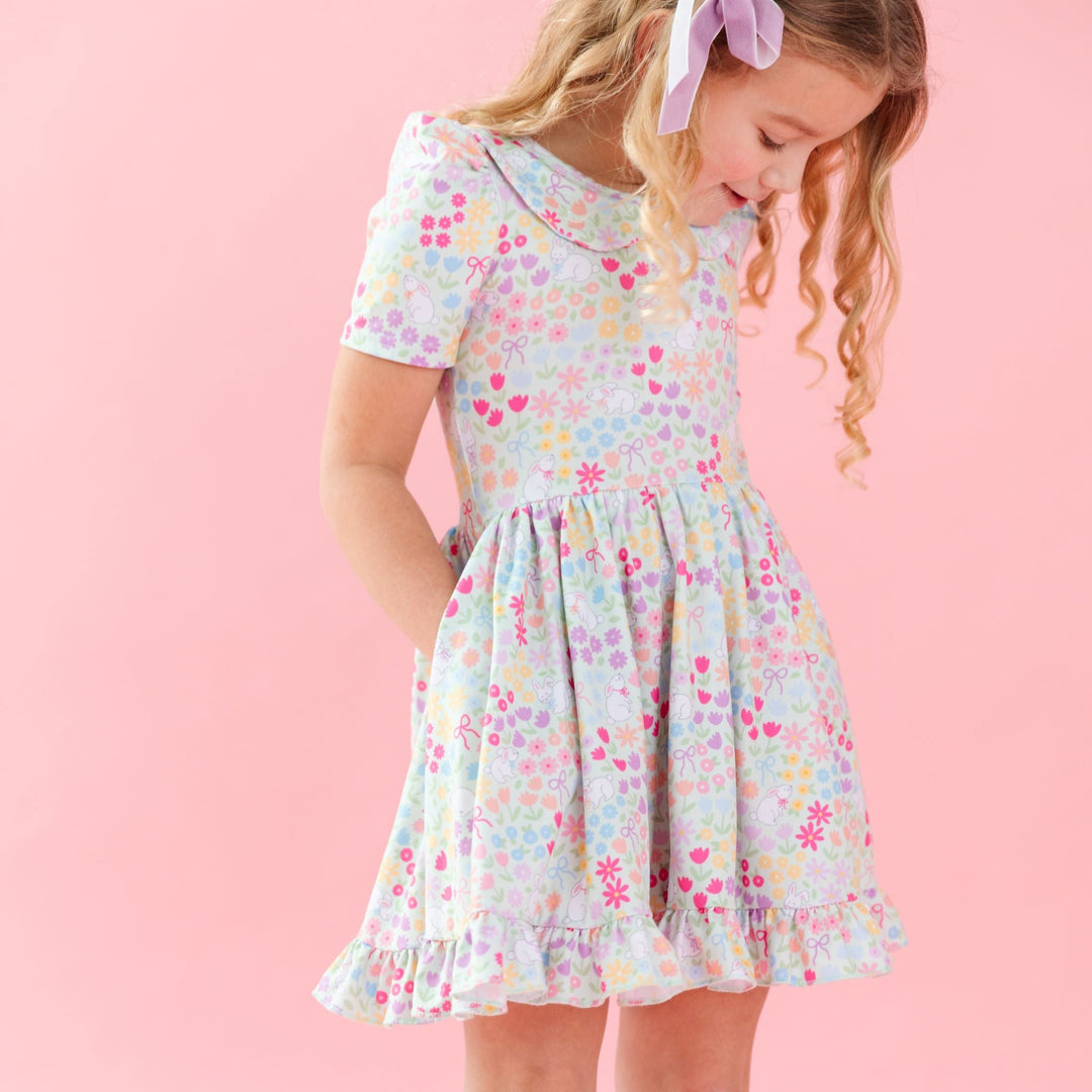 little girl in easter twirl dress with peter pan collar in a pastel flower and bunny print and lavender velvet hair bow 