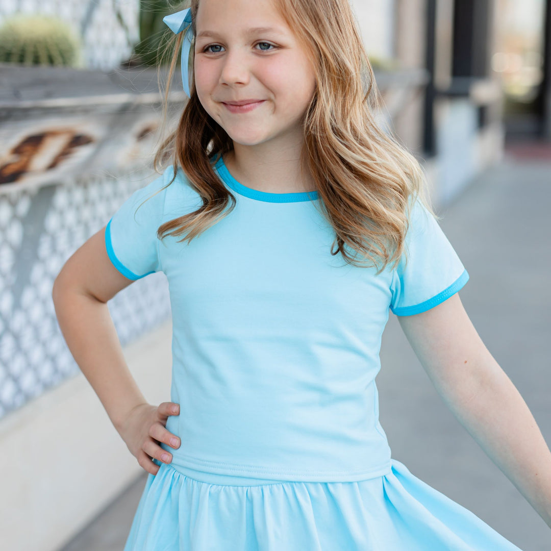 little girl in blue fitted cotton blend tee with bright blue binding on sleeve and neckline paired with matching skirt