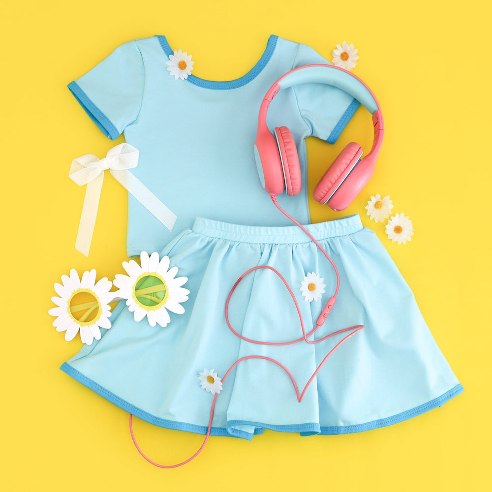 styled flatlay of girls matching summer t-shirt and skort in blue with electric blue binding 