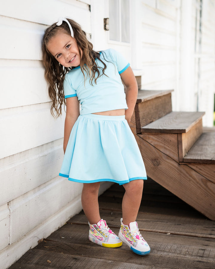 little girl in matching blue fitted tee and skort with contrast blue binding and colorful sneakers for summer