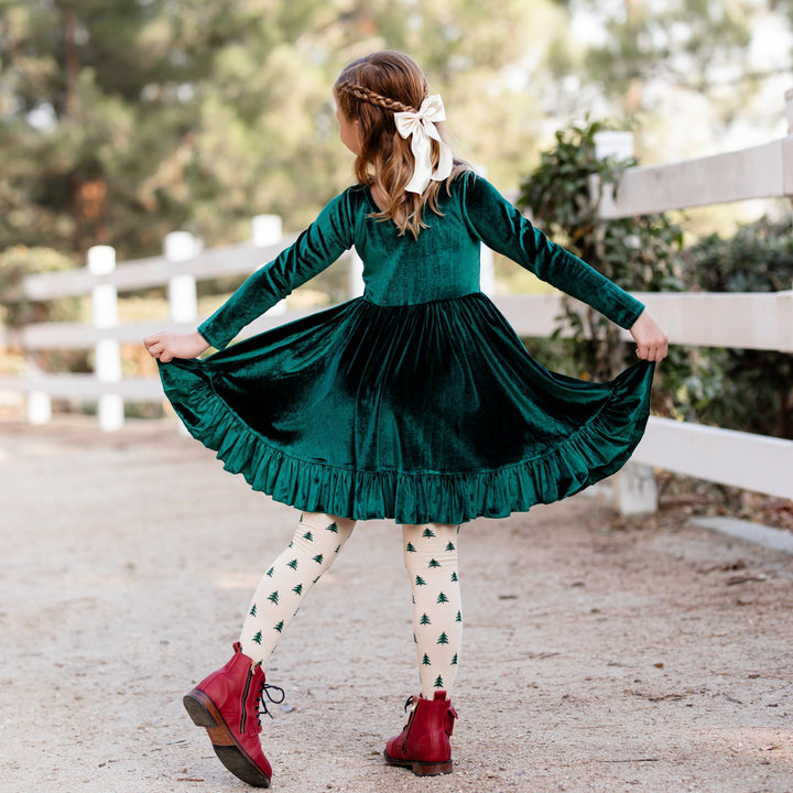 girl wearing green velvet christmas dress with tree tights and matching ivory satin bow