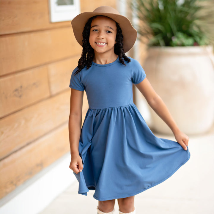 little girl wearing denim blue cotton dress and light brown hat