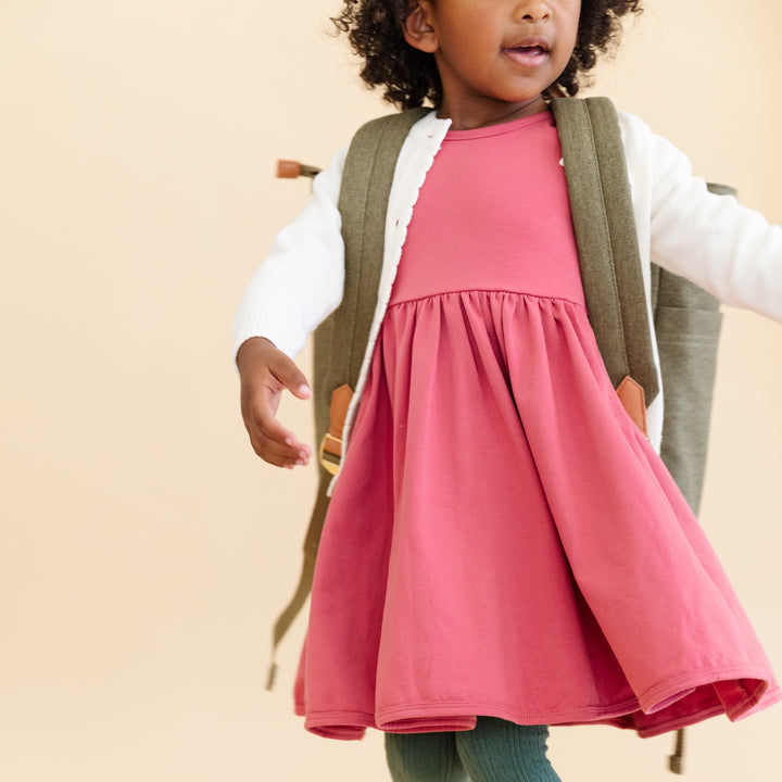 little girl wearing a backpack and pink rose everyday dress with cute ivory cardigan over it