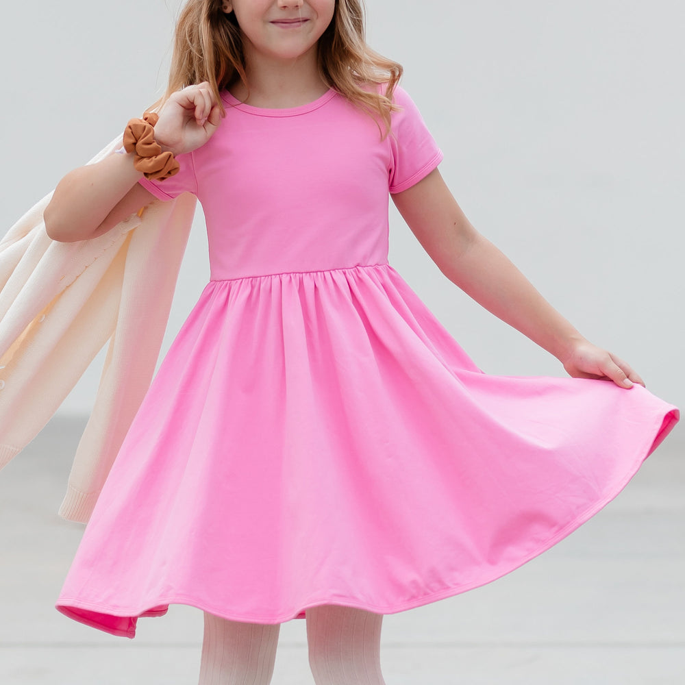 little girl mid twirl wearing pink cotton everyday dress with pockets