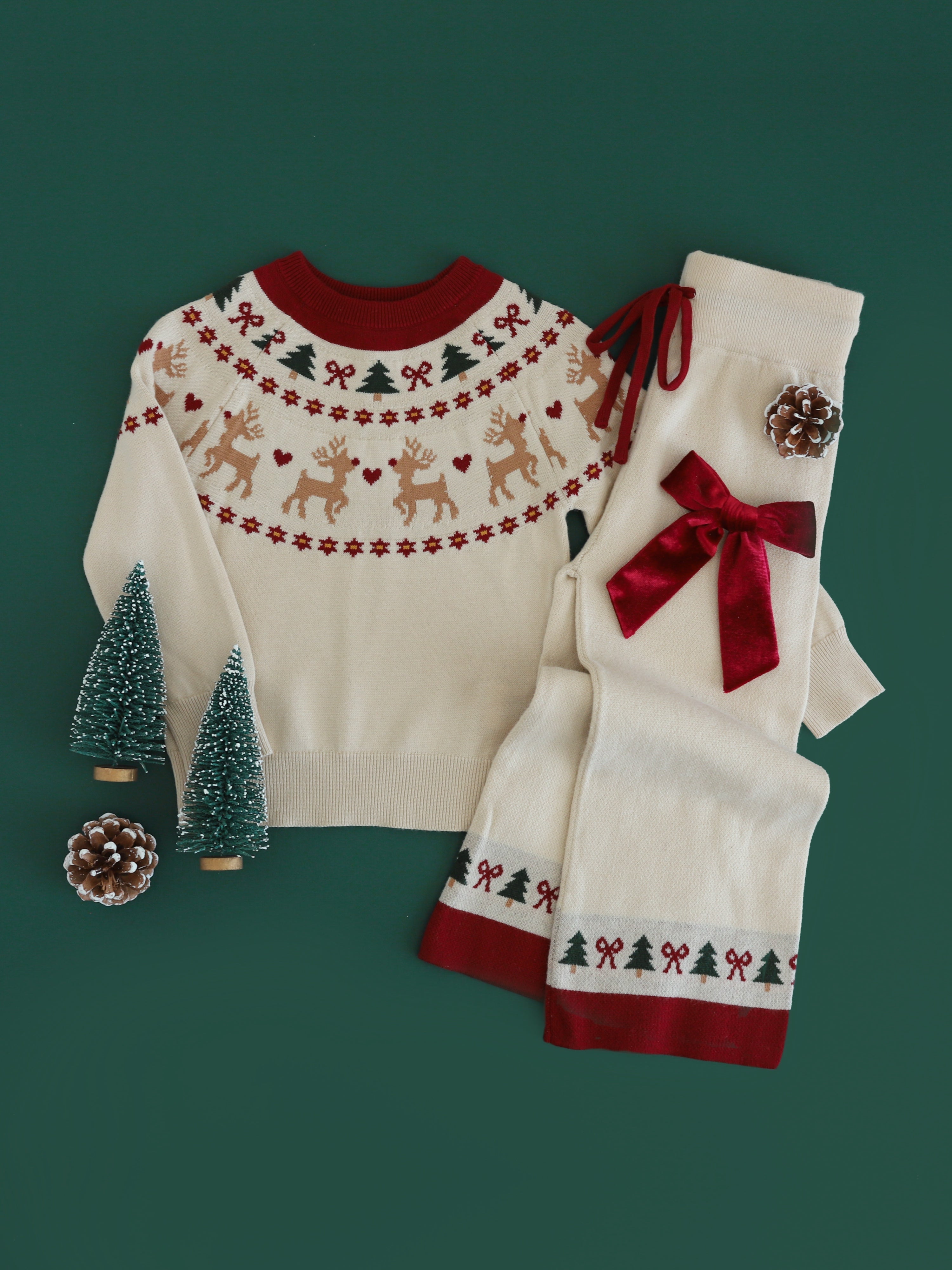 girls' cream knit pullover sweater with fair isle reindeer, tree and bow print paired with matching cream knit sweater pants with bow and tree print at the ankle