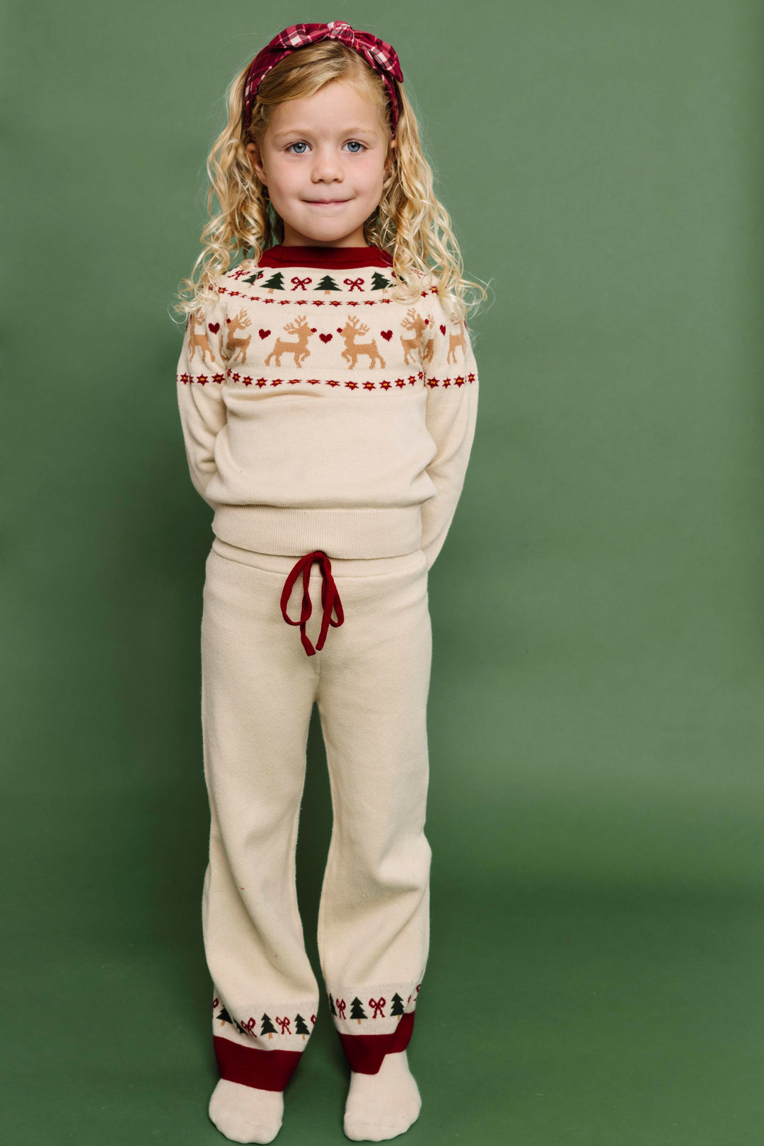 young girl in cream pullover sweater and pant set with crimson and forest green fair isle print and matching crimson plaid headband for Christmas
