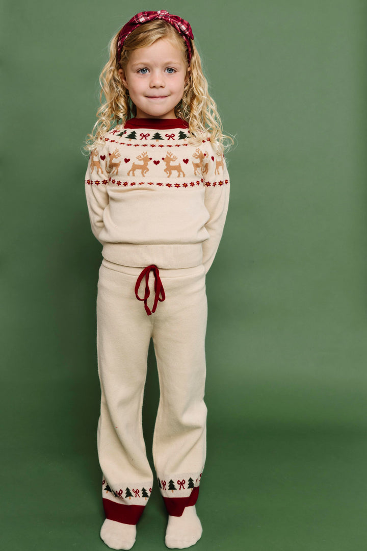 young girl in cream pullover sweater and pant set with crimson and forest green fair isle print and matching crimson plaid headband for Christmas