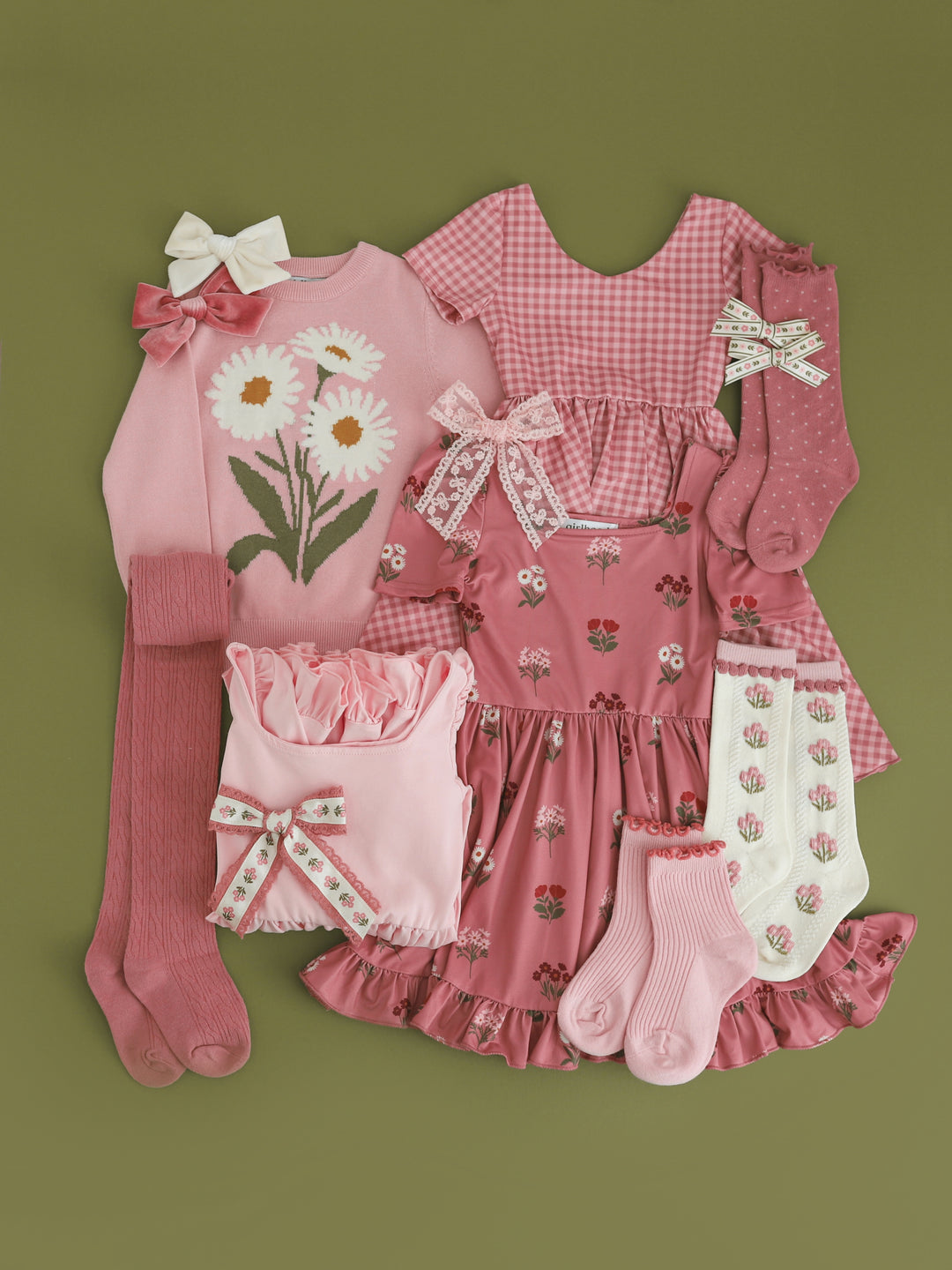 flat lay photo of girls mix and match dresses, socks, tights, sweaters and bows in shades of pink