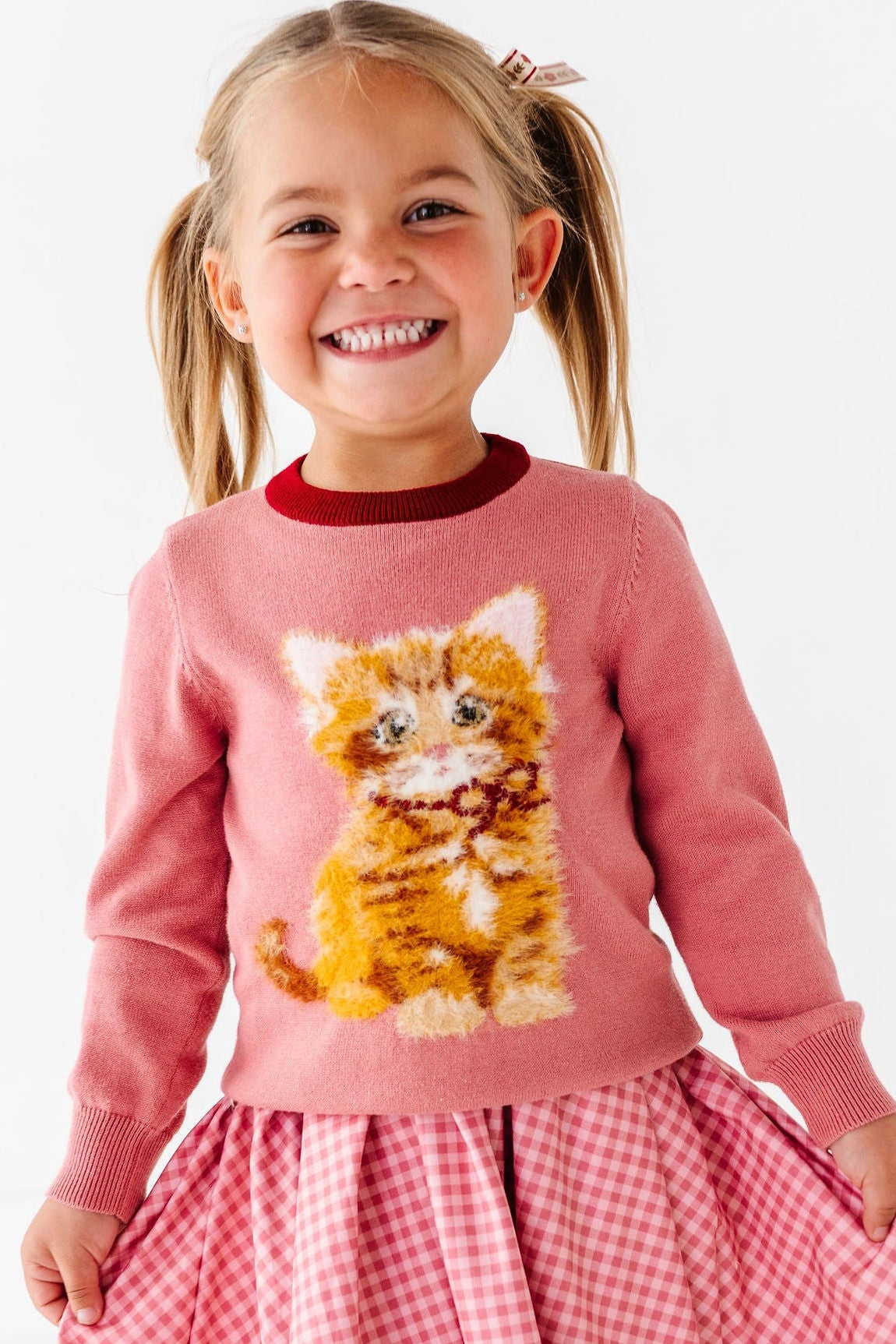 girl wearing sweater with fluffy orange cat and pink gingham dress
