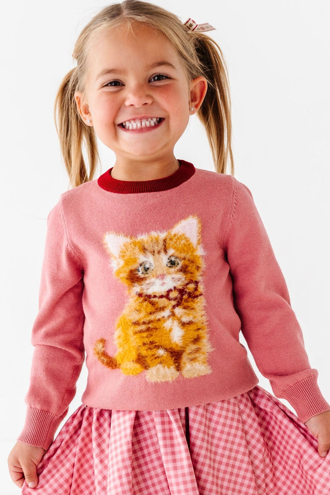girl wearing sweater with fluffy orange cat and pink gingham dress