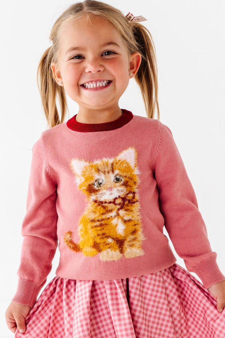 girl wearing sweater with fluffy orange cat and pink gingham dress