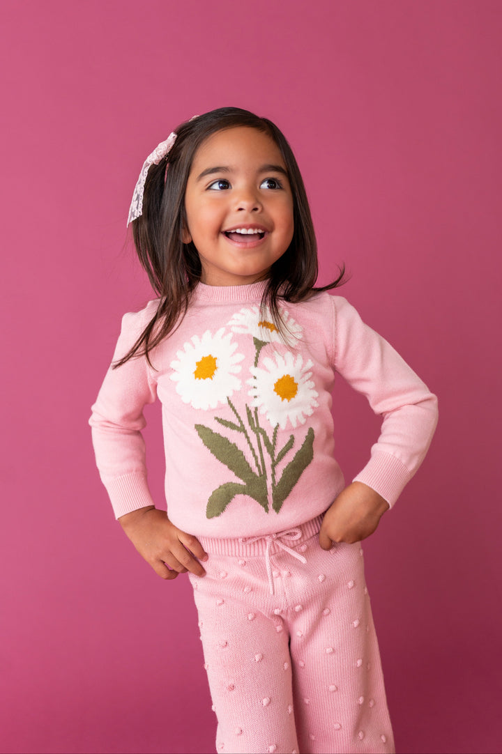 young girl in light pink sweater with white daisy design and 3D raised bubble design pants for fall