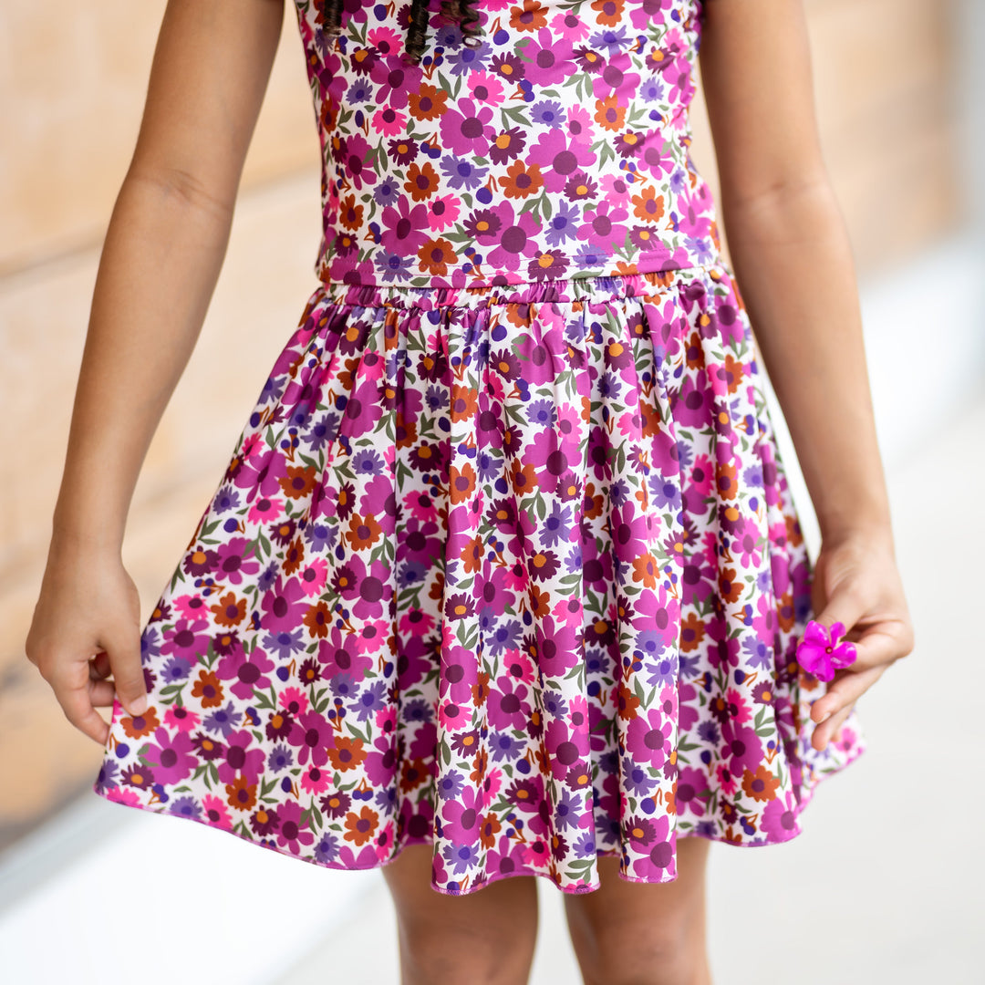 little girl holding tiny flower in fall floral skirt in shades of plum with matching top