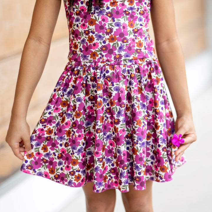 little girl holding tiny flower in fall floral skirt in shades of plum with matching top