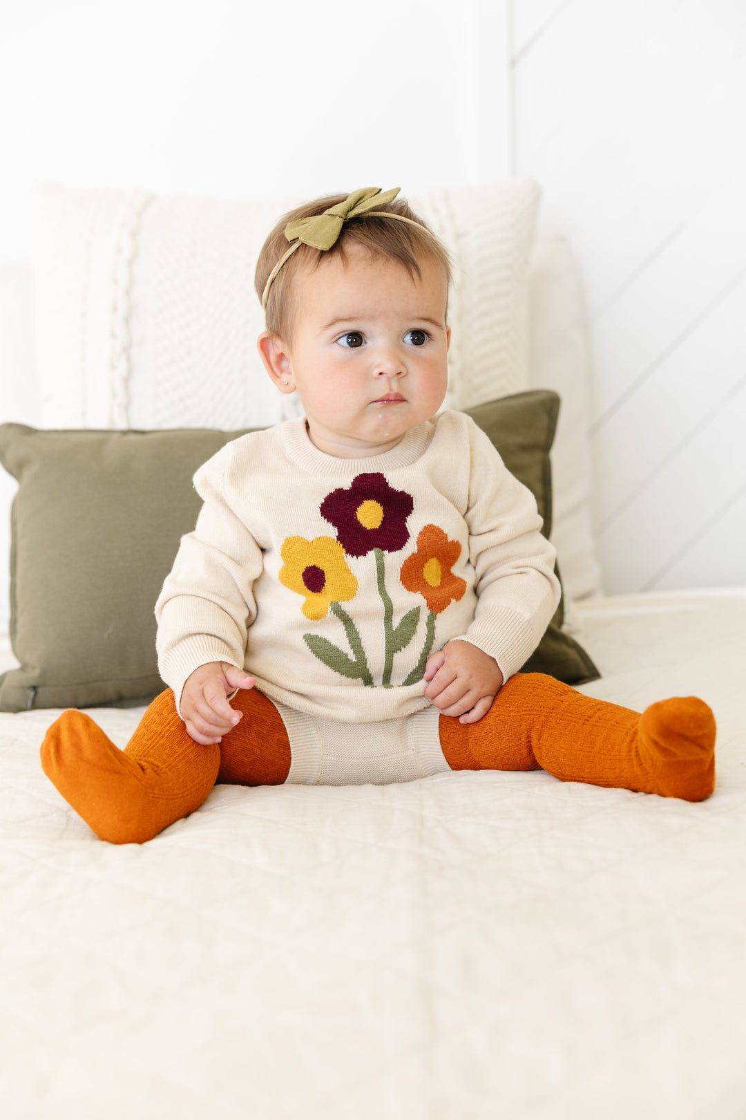 baby girl in cream 100% cotton knit pullover sweater with fall flower design paired with matching cream sweater bloomers, orange cable knit tights and matching olive hairbow on nylon