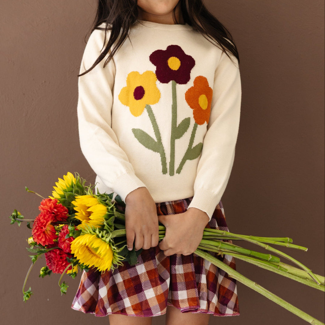 little girl holding fall flowers in cream cotton knit sweater with fall bouquet design and burgundy fall plaid velvet skort 
