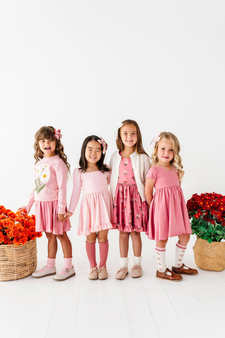 little girls wearing coordinating pink outfits for fall with matching hair bows and socks