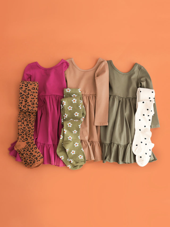 flat lay photo of girls' cotton blend twirl dresses in raspberry, mocha and olive with matching patterned tights for fall