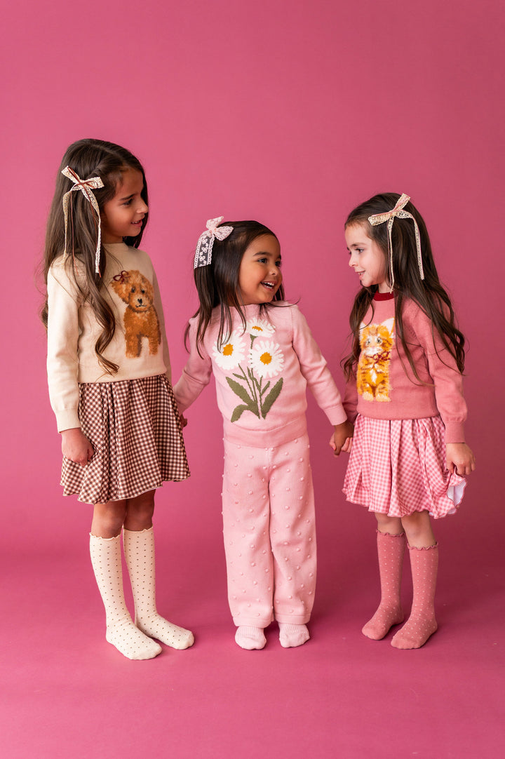 3 little girls wearing fall graphic sweaters with coordinating dresses, knit pants and hair bows