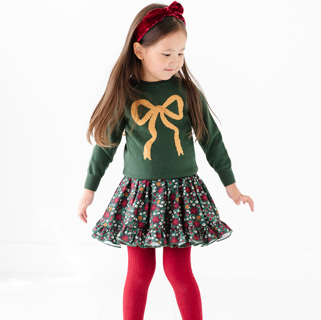 girls forest green knit pullover sweater with gold bow detail, poinsettia twirl dress and matching crimson accessories for Christmas