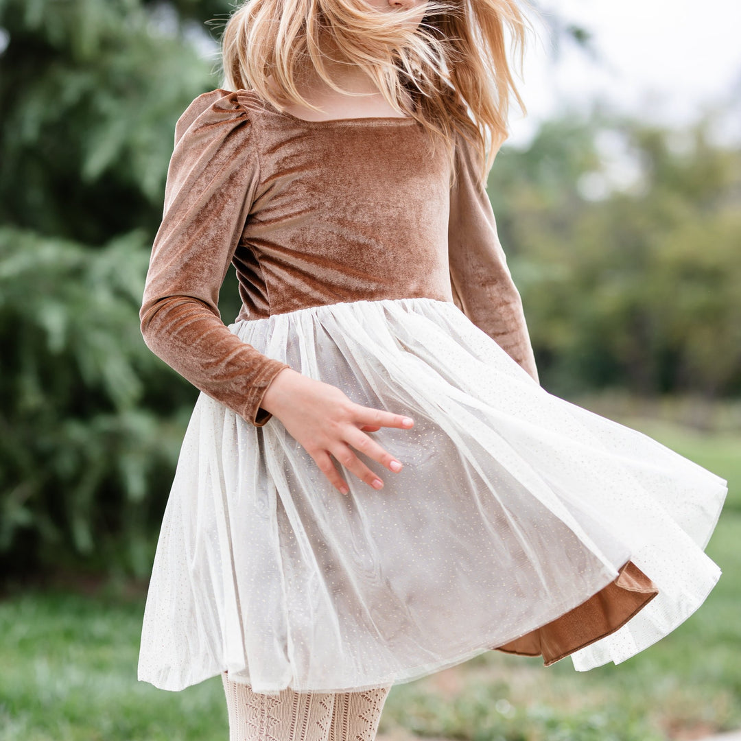 closeup of little girl twirling in gold velvet party dress with sparkly cream tulle skirt