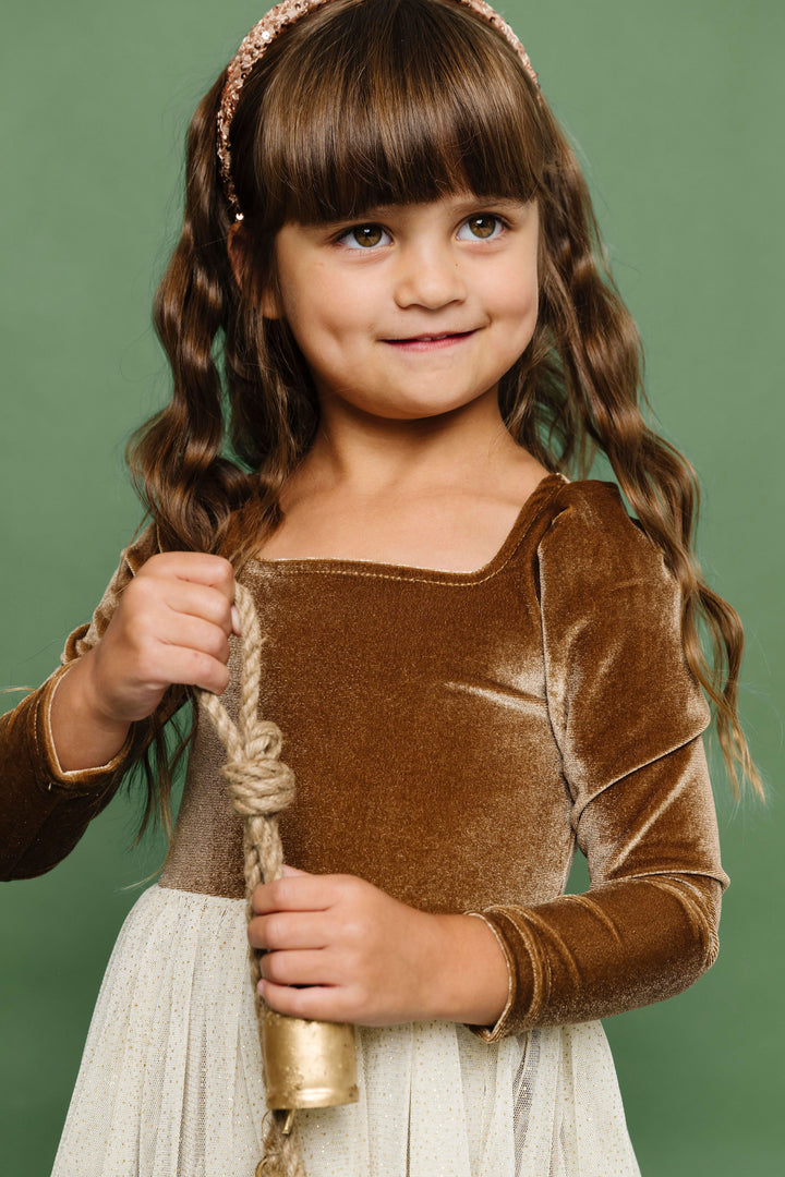 little girl holding Christmas bell in golden brown velvet tutu dress and gold sequin headband