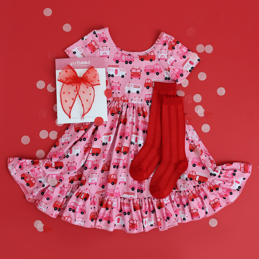 girl's styled outfit flat lay featuring Valentine's firetruck print twirl dress, matching red knee highs and sheer red bow