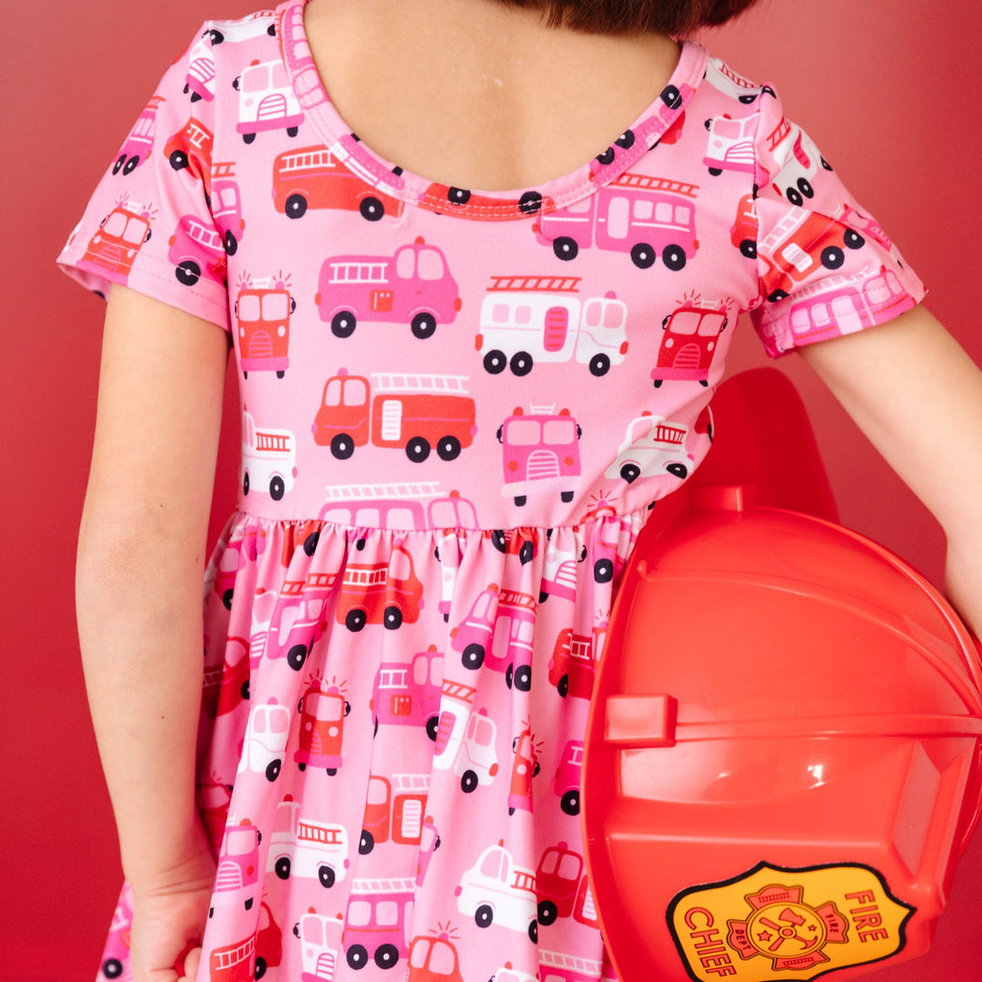 close up of little girl's scoop back twirl dress in pink, red and white firetruck print for Valentine's Day